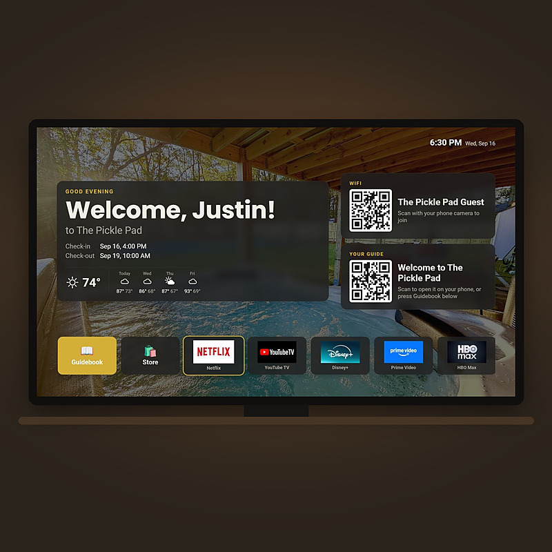 A living room television showing Welcome, Justin! with the dates of the stay, the weather, the WiFi and guide QR codes, and the streaming app tiles